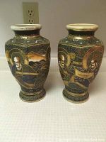 Pair of Satsuma vases showing detailed hand-painted scenes of men in traditional robes with gold and black designs.