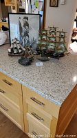Four model ships and a framed nautical picture displayed on countertop