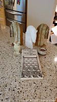 Full view of horse bookends, white stone horse figurine, mini vase, candle holder, and wall art on countertop.