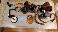 Full lot overview showing various lenses, camera body with case, accessories, and film.