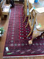 Full view of red area rug under dining table showing field pattern and border