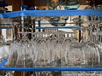 Shelf view showing rows of small stemmed cordial glasses and larger wine glasses with Lismore pattern