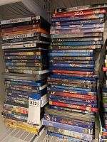 Stack of DVD cases including Disney and other titles such as The Family Stone, Queen, The Best Exotic Marigold Hotel, Sleepless in Seattle, National Treasure, and Pirates of the Caribbean.