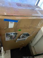 Photo of large cardboard box labeled 'Holy Family Santa' containing yard decor items, sealed with tape.