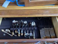 Flatware arranged in open drawer showing spoons, forks, serving pieces and knives.