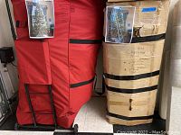 Red canvas storage bag and taped cardboard box containing tree sections and branches.