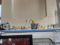 Shelf with assorted figurines including small animal, angel, and nurse figurines in various colors and styles.