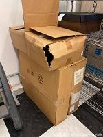 Four cardboard boxes stacked, two visible with some damage to the top box.