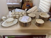 Overview of all china pieces arranged on table, including platters, plates, cups, sugar bowl, shakers