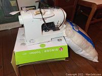 Singer Tradition 2217 sewing machine sitting on box with large bag of cluster fiber beside it