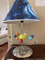 Lamp showing entire piece with solar system planets arranged around central sun and starry pattern lampshade
