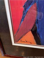 Close-up of signature on bottom corner of framed art print showing bright colored abstract design with signature that appears to read 'Taubmey' or similar.