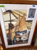 Front view of framed print depicting an antique scene with a large wooden sailing ship, clock, and vintage items.