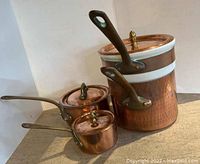 Overall view of three copper pots with lids