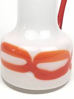 Close-up detail of the red abstract design on the jug's white glass body, showing smooth glossy finish and no mold lines.
