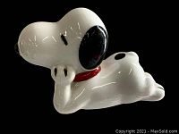 Side angle of white porcelain Snoopy figurine showing black ears, nose, and painted red collar.