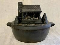 Front view of cast iron steamer with cabin shaped lid on top.