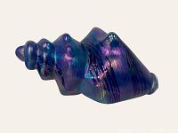 Side view of bright blue carnival glass shell showing its glossy iridescent surface, texture and conch shape.