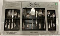 Full view of flatware set in original packaging, showing all cutlery pieces arranged in three groups with a label indicating 70-piece set and brand 'Gorham Meredith'.