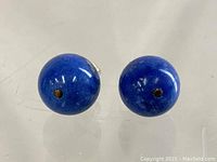 Close-up of the spherical lapis lazuli stones showing deep blue color and slight surface markings.