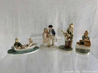 Lot of four fishing themed Sebastian miniature ceramic figurines displayed together on a clear shelf against a white background.