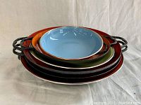 Stacked view of six enamelware pans showing colors and handles