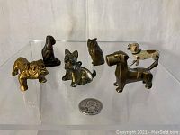 Front view of all six small metal animal figurines on clear display, showing scale with a quarter coin.