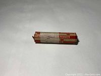Sealed paper roll containing unsearched wheat pennies from 1924, marked with red and white label indicating 50 cents in pennies.