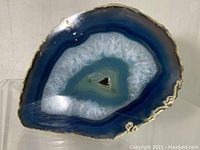 Front view showing polished blue and white agate geode with crystalline center and natural rough edges.