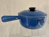 Side view of the vintage blue Le Creuset enamel sauce pot with handle and lid knob visible.