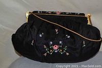 Front view of black satin purse with colorful floral embroidery and gold-tone chain handle.