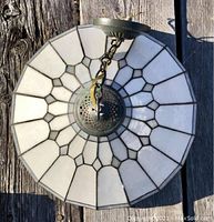 Top-down view of round Tiffany style lampshade showing white resin panels and brass fittings on wood surface.