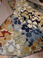 Close-up of multi-color abstract floral pattern and edge with backing folded back to show texture and colors.