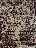 Close-up photo showing the beige background with red and black ornate floral patterns.