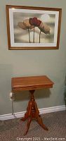Full view of vintage Eastlake style wooden table under the framed print.