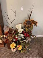 Large collection of assorted artificial flowers in various vases including a sunflower arrangement and faux branches.