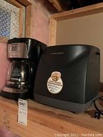 Photo showing Hamilton Beach bread maker and Black and Decker coffee maker on a wooden shelf.