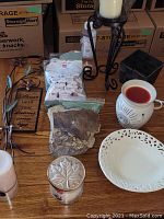 Various candles and wax burner items arranged on wooden table with boxes in background