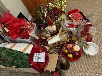 Photo showing boxed artificial tree, red mesh bows, assorted ornaments, a Santa plush figure, and floral arrangements.
