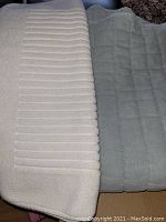 Comforter and bath mat laid out showing textures and colors