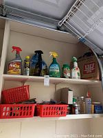 Shelf containing various spray bottles of garden and household chemicals such as AntOut, Weed & Grass Killer, WD-40, alongside storage baskets and jars.