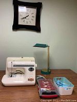 Overview of sewing machine, desk lamp and wall clock displayed on tabletop