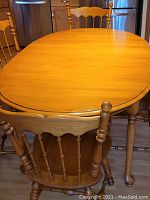 Top view of the oval wooden dining table with spindled back chair in front.