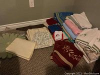 Various folded towels, cloths, placemats, and table linens in different colors and patterns