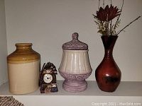 Full view of lot showing glazed clay jar, small Hound and Hunt Club boat clock, glazed pottery jug, and resin vase with artificial flowers