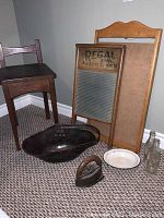 Photo showing all vintage items including chair, metal basket, washboard, calendar frame, coke bottles, enamel bowl and vintage iron with stand