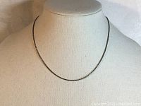 Necklace displayed on a white fabric mannequin neck showing length and shiny silver rope design.