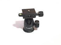 Canon branded black tripod ballhead showing quick release plate, adjustment knobs, and bubble level on a white background.