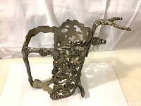 Side angle view showing the embossed grape vine details and handle of the brass bottle holder.