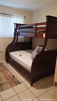 Full view of wooden bunk bed with twin top and double bottom, showing ladder and mattress bases with no mattresses or box springs.